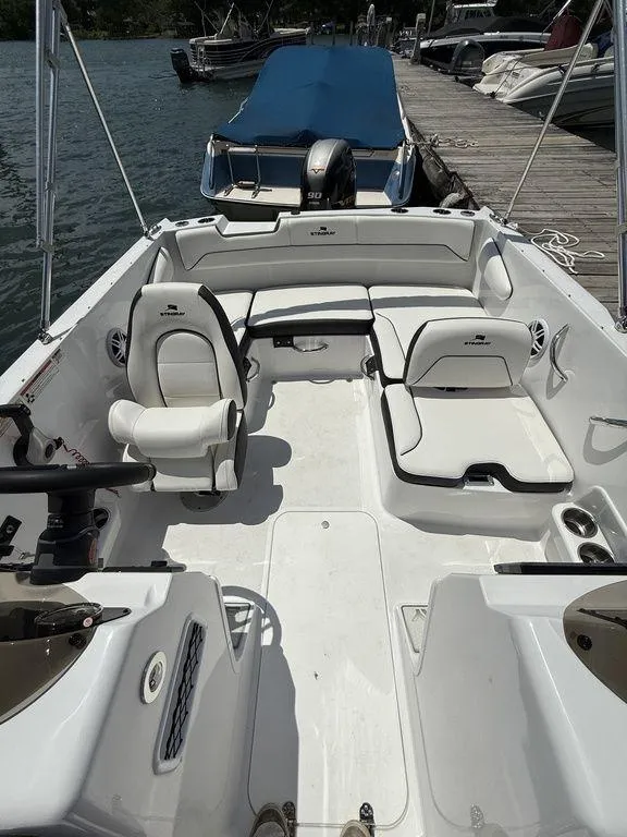 Slide: The Image of 2025 Stingray 172SC boat interior with white seating, docked by the water. - 6