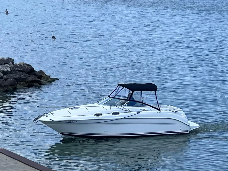Slide: The Image of 2001 Sea Ray 260 Sundancer boat on calm water near rocky shore. - 0