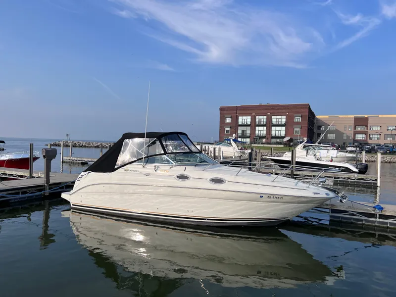 Slide: The Image of 2001 Sea Ray 260 Sundancer docked at marina, clear sky, waterfront buildings in background. - 2