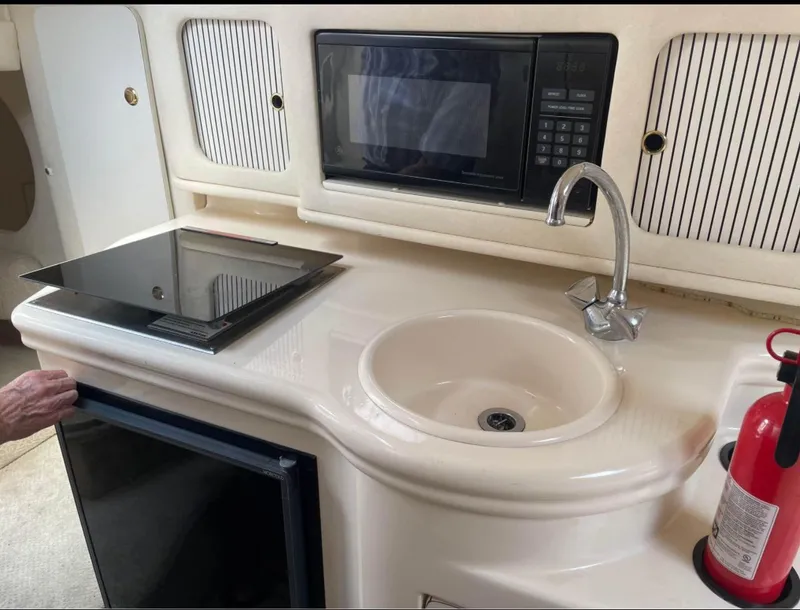 Slide: The Image of 2001 Sea Ray 260 Sundancer kitchenette with sink, stove, microwave, and fire extinguisher. - 8
