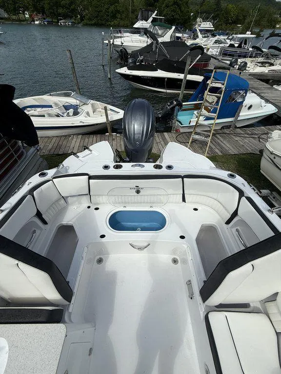 Slide: The Image of 2025 Stingray 231DC boat interior at a marina, featuring spacious seating and a central compartment. - 11