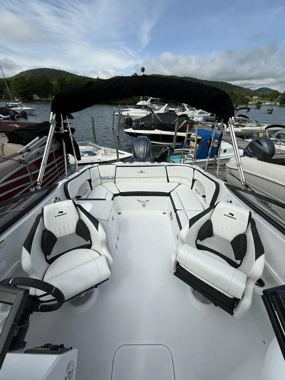 Slide: The Image of 2025 Stingray 231DC boat interior with white seating, docked at a marina. - 12
