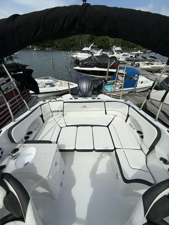 Slide: The Image of 2025 Stingray 231DC boat interior with white seating, docked at a marina. - 13