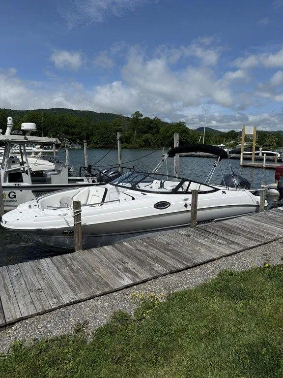 Slide: The Image of 2025 Stingray 231DC boat docked by a scenic lake under a clear blue sky. - 3