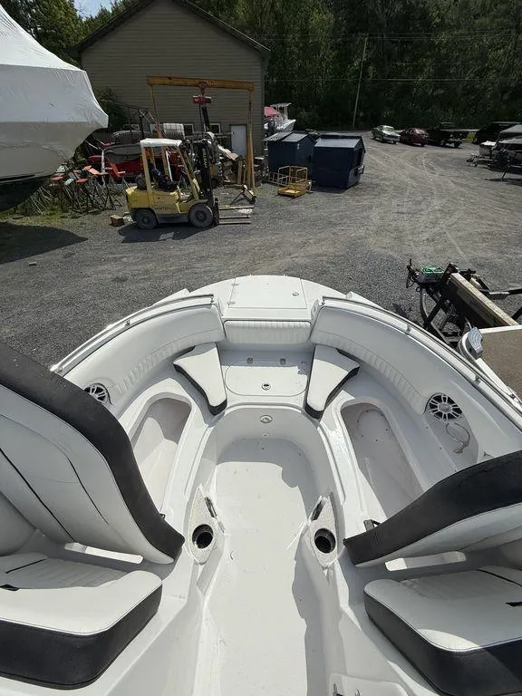 Slide: The Image of 2025 Stingray 231DC boat interior with seating, parked in a yard with equipment. - 31