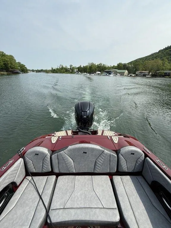 Slide: The Image of 2025 Stingray 23 OSX boat cruising on a scenic lake with lush greenery. - 21