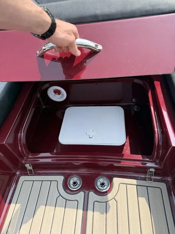 Slide: The Image of 2025 Stingray 23 OSX boat storage compartment with red finish and white hatch. - 23