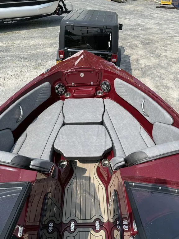 Slide: The Image of 2025 Stingray 23 OSX boat with red and gray interior, parked on a trailer. - 27
