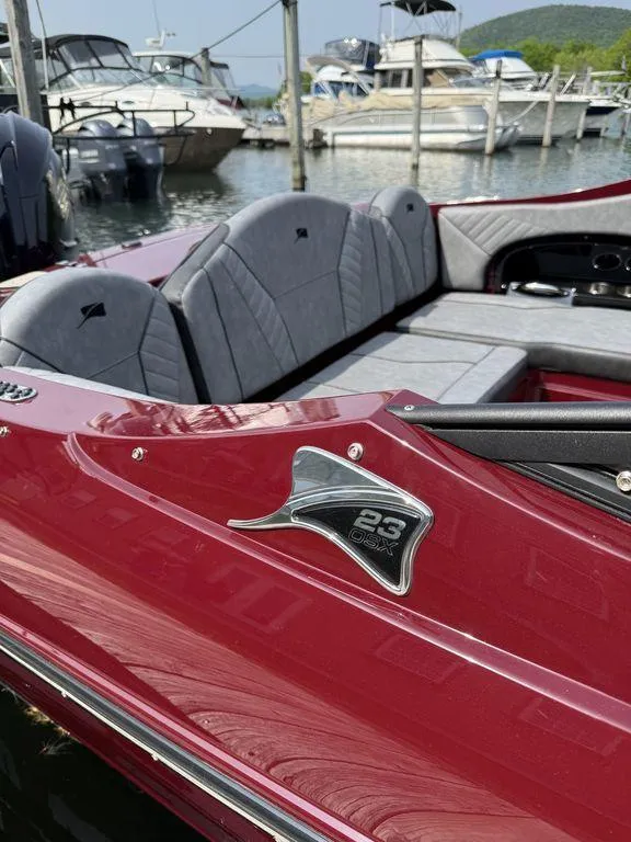 Slide: The Image of 2025 Stingray 23 OSX boat with red exterior and gray interior, docked at a marina. - 3