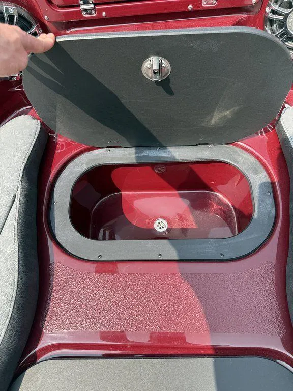 Slide: The Image of 2025 Stingray 23 OSX boat storage compartment with open lid, red interior. - 33