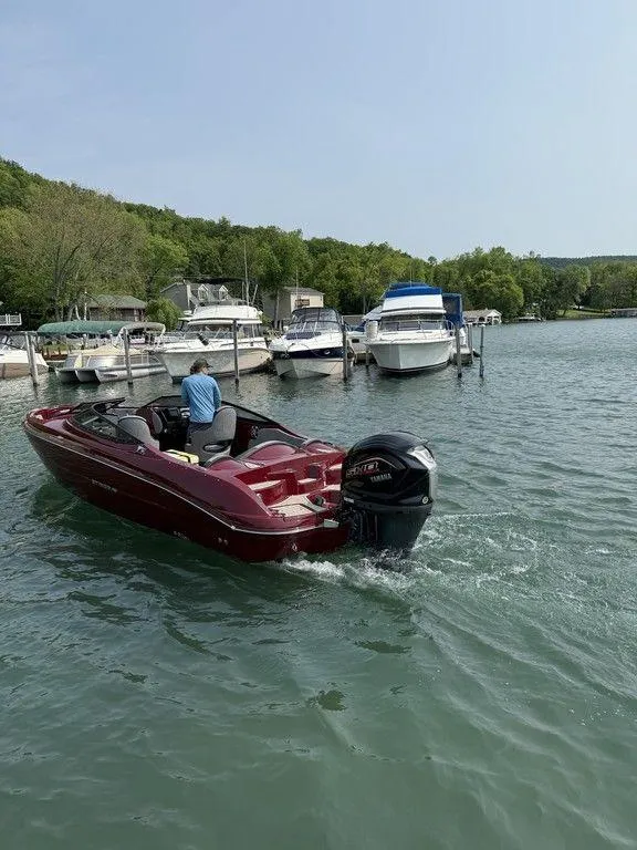 Slide: The Image of 2025 Stingray 23 OSX boat cruising on a lake near a marina. - 5