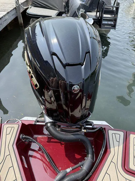 Slide: The Image of 2025 Stingray 23 OSX boat with a sleek black outboard motor, docked on calm water. - 7