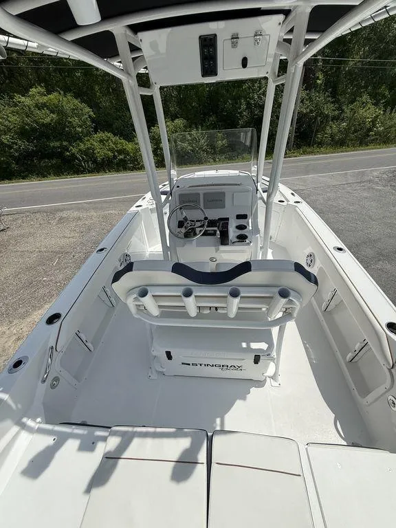 Slide: The Image of 2025 Stingray 216CC boat interior with console, seating, and steering wheel, parked outdoors. - 13