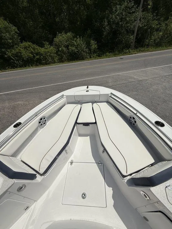 Slide: The Image of 2025 Stingray 216CC boat with white cushioned seating, parked near a road. - 20