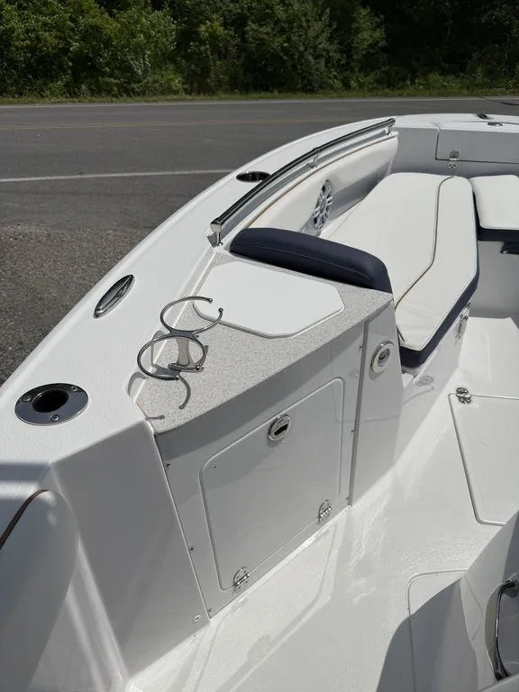 Slide: The Image of 2025 Stingray 216CC boat interior with white seating and cup holders, parked near a road. - 22