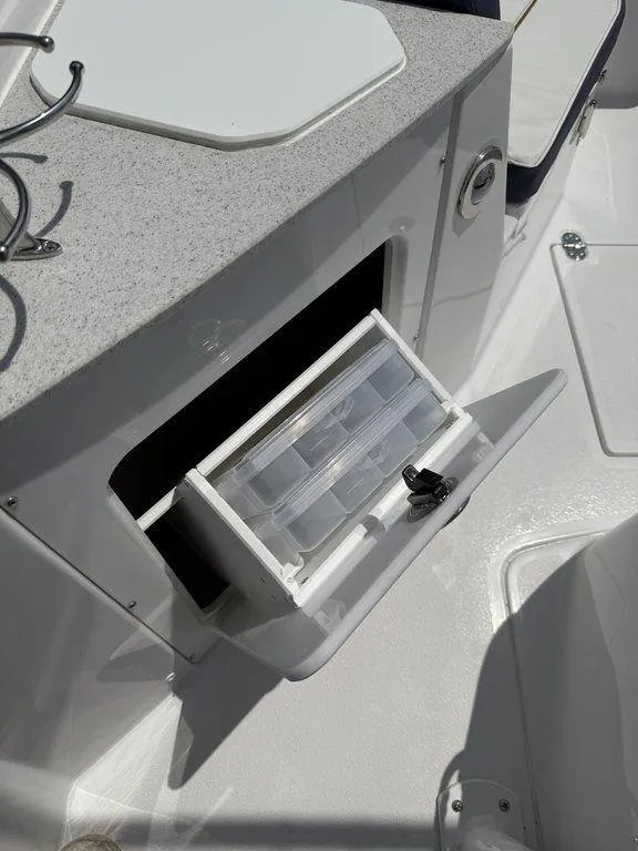 Slide: The Image of 2025 Stingray 216CC boat with open storage compartment and tackle box. - 23