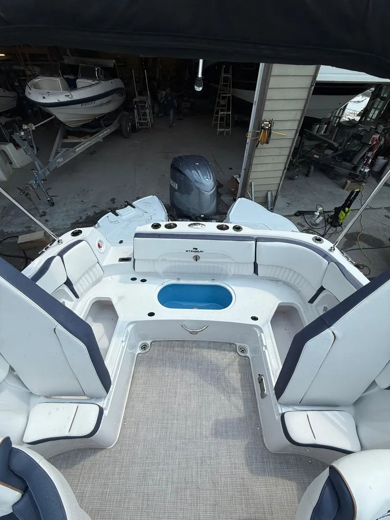 Slide: The Image of 2025 Stingray 211DC boat interior with seating and motor in a garage setting. - 10