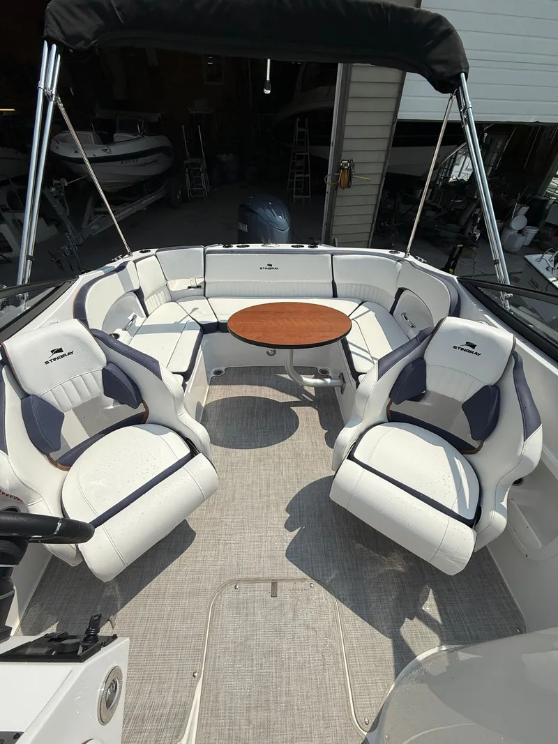 Slide: The Image of 2025 Stingray 211DC boat interior with white seating and a central wooden table. - 11