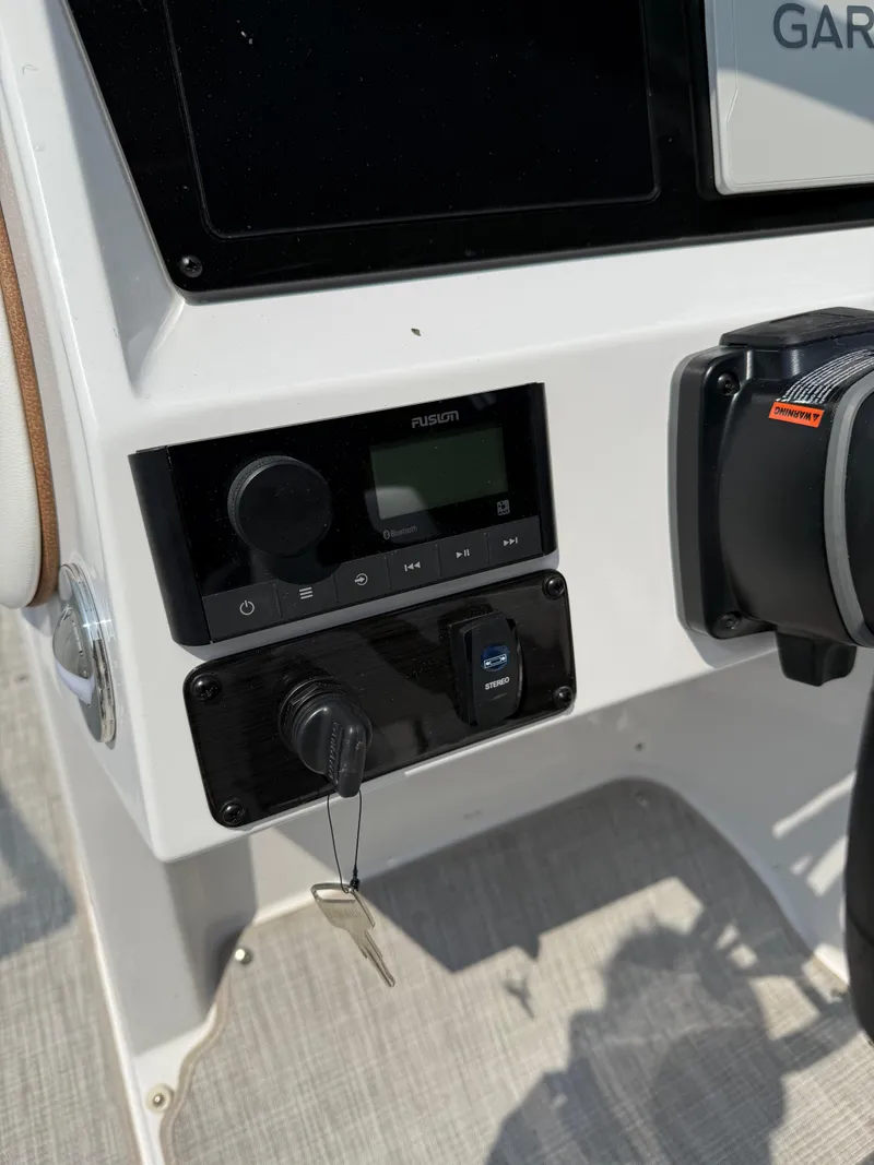 Slide: The Image of Control panel of 2025 Stingray 211DC boat with key ignition and audio system. - 14