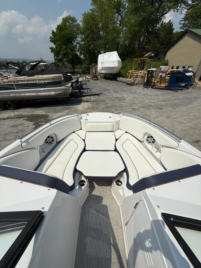 Slide: The Image of 2025 Stingray 211DC boat interior with white seating, docked outdoors. - 24