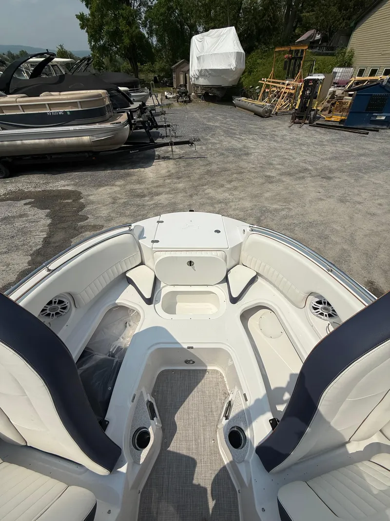 Slide: The Image of 2025 Stingray 211DC boat interior with seating, parked outdoors. - 26