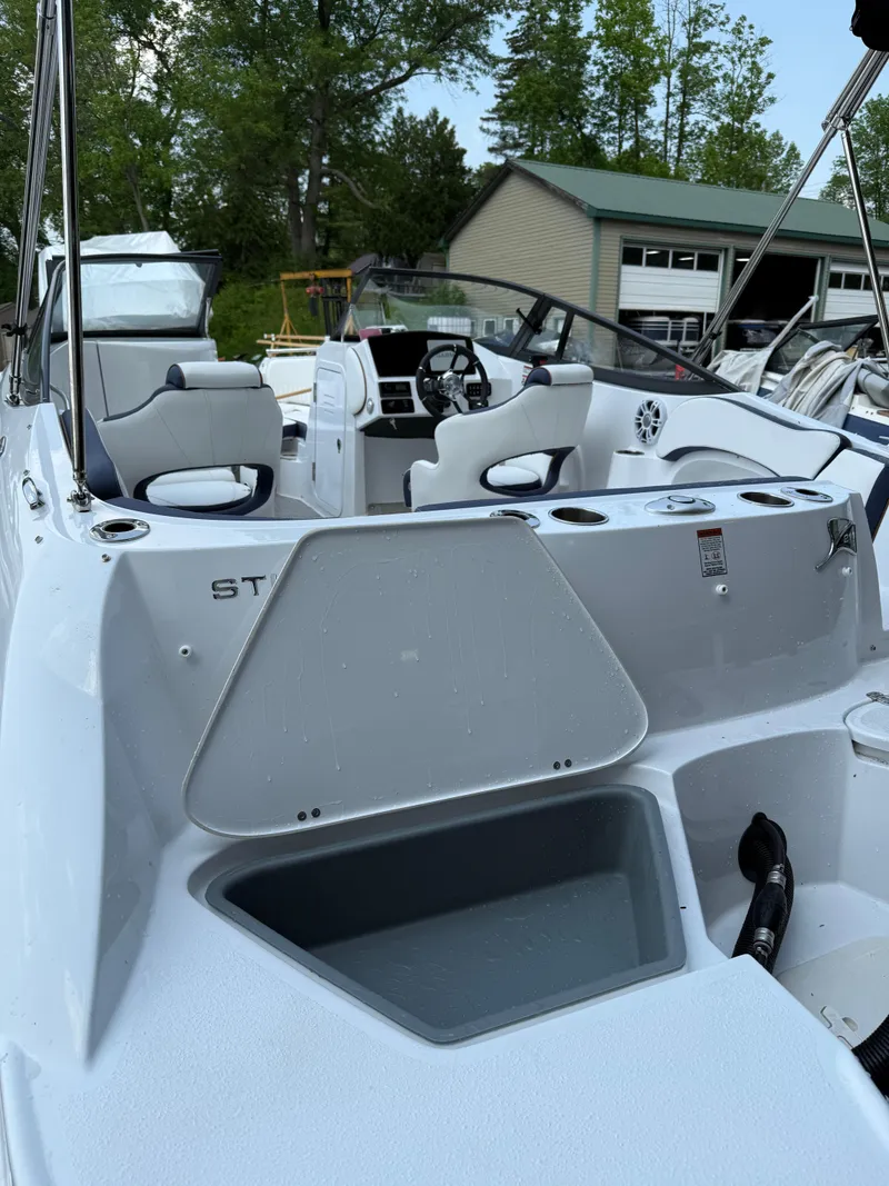 Slide: The Image of 2025 Stingray 211DC boat interior with seating and control panel, docked near a boathouse. - 5