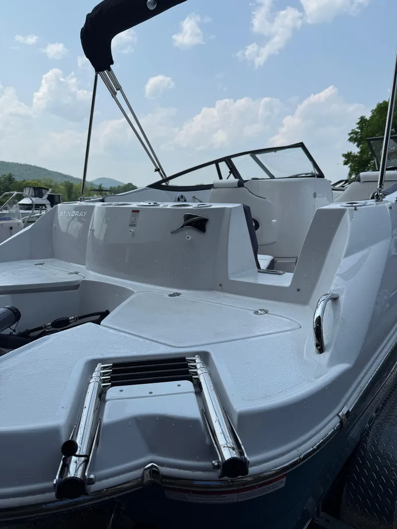 Slide: The Image of 2025 Stingray 211DC boat with sleek design, ladder, and windshield under a partly cloudy sky. - 8