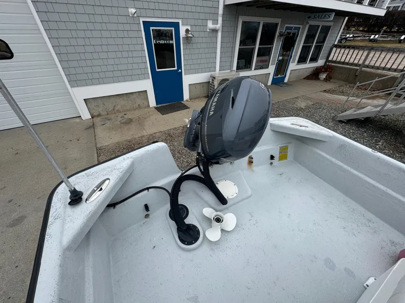 Slide: The Image of 2003 Maritime 1690 boat with outboard motor, parked near a building with blue doors. - 2