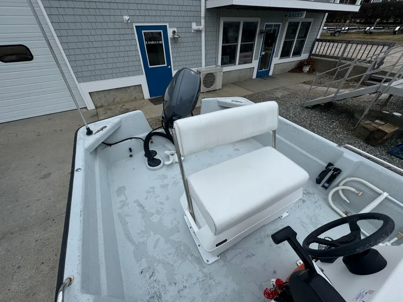 Slide: The Image of 2003 Maritime 1690 boat with white seating and steering wheel, docked near a building. - 6