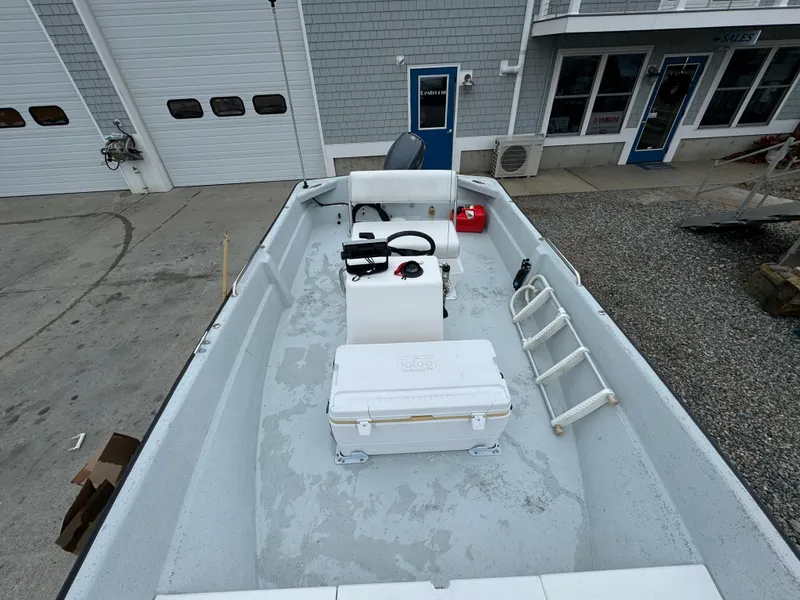 Slide: The Image of 2003 Maritime 1690 boat with open deck, ladder, and storage box, parked near a building. - 8