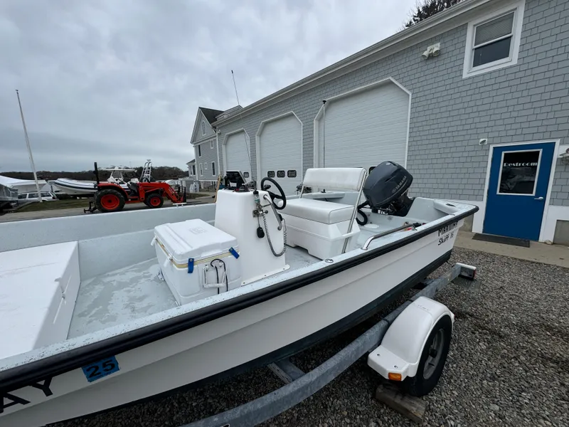 Slide: The Image of 2003 Maritime 1690 boat on trailer, parked near a building with tractor in background. - 9