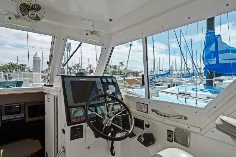 Slide: The Image of 2007 Albin 28 Tournament Express helm with marina view, featuring steering wheel and navigation equipment. - 10