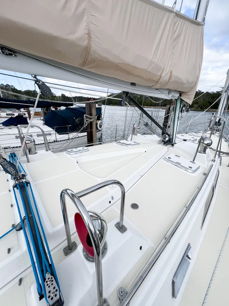 Slide: The Image of Sailboat deck view of 1998 Saga 43, featuring rigging and marina backdrop. - 18