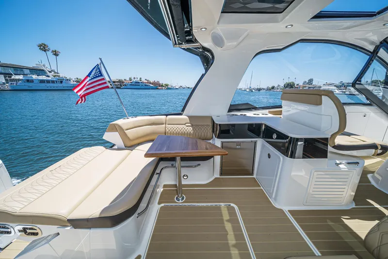 Slide: The Image of 2023 Sea Ray Sundancer 370 OB interior with seating, table, and American flag on water. - 18