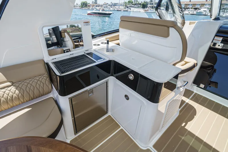 Slide: The Image of 2023 Sea Ray Sundancer 370 OB interior with kitchenette and seating, overlooking marina. - 19
