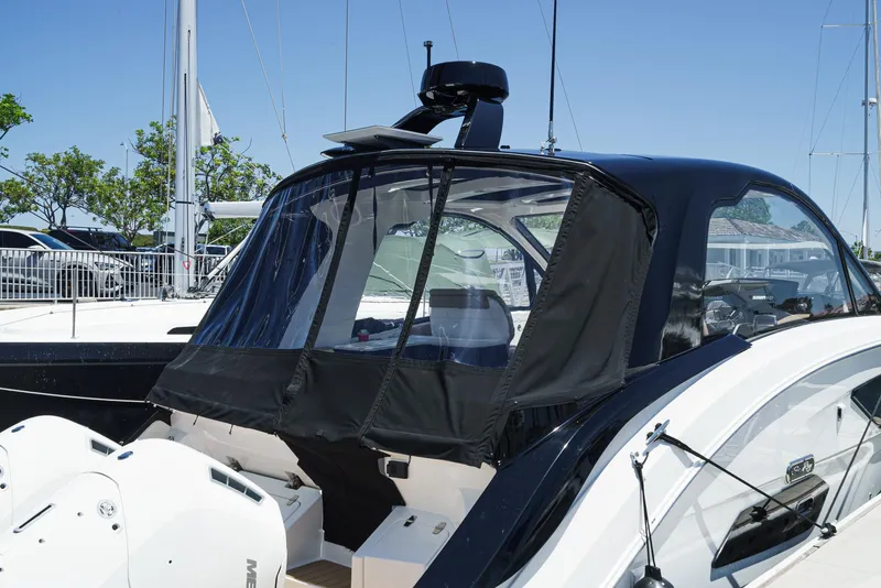 Slide: The Image of 2023 Sea Ray Sundancer 370 OB with black canopy, docked under clear blue sky. - 40