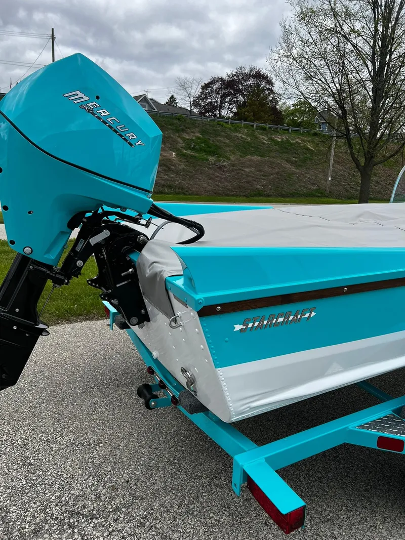 Slide: The Image of 2025 Starcraft 57 SKI CHAMP boat with Mercury outboard motor, parked on a trailer. - 4