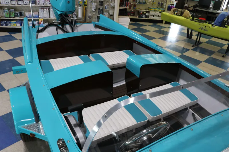 Slide: The Image of 2025 Starcraft 57 Ski Champ boat with turquoise and white seating in a showroom. - 10