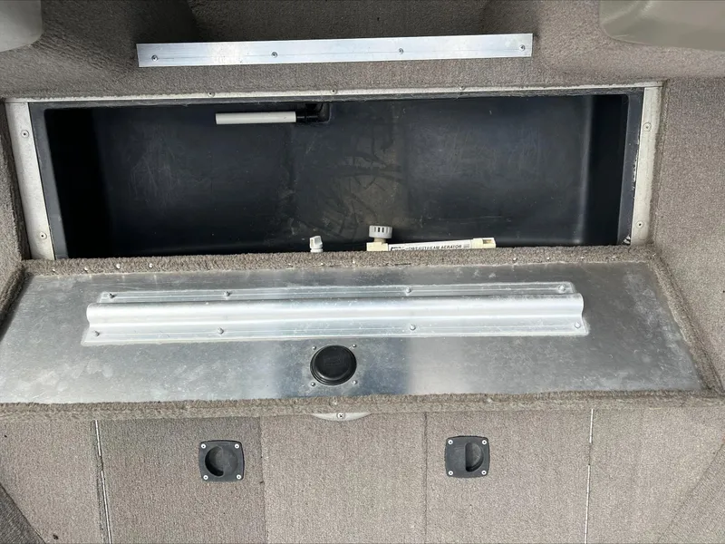 Slide: The Image of 1998 Tracker Targa 185 WT boat storage compartment with metal latch and carpeted interior. - 2