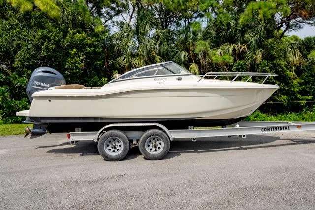 Slide: The Image of 2021 Scout 210 Dorado boat on trailer, side view, with Yamaha engine, surrounded by trees. - 3