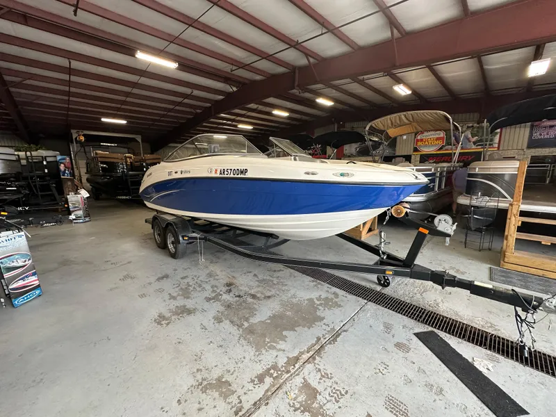 Slide: The Image of 2009 Yamaha Boats SX210 in a storage facility, blue and white hull on a trailer. - 6