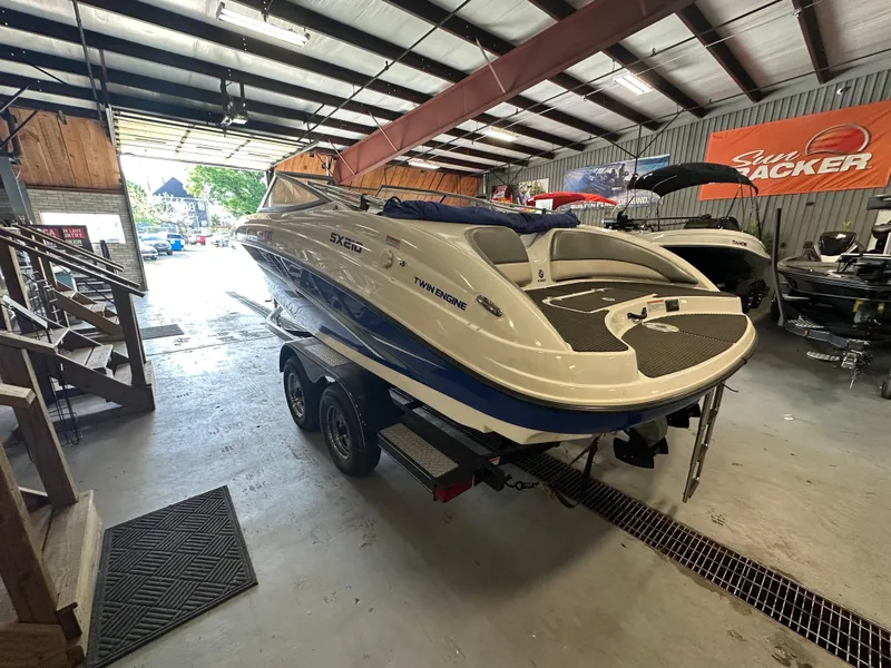 Slide: The Image of 2009 Yamaha SX210 boat in a garage, on a trailer, with a sleek white and blue design. - 8