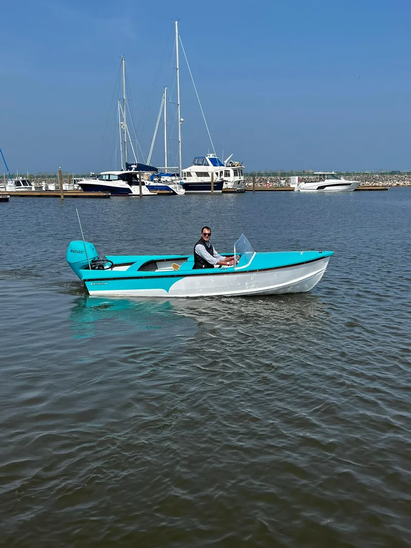 Slide: The Image of A turquoise Starcraft 57 SKI CHAMP boat from 2025 on calm waters near a marina. - 6