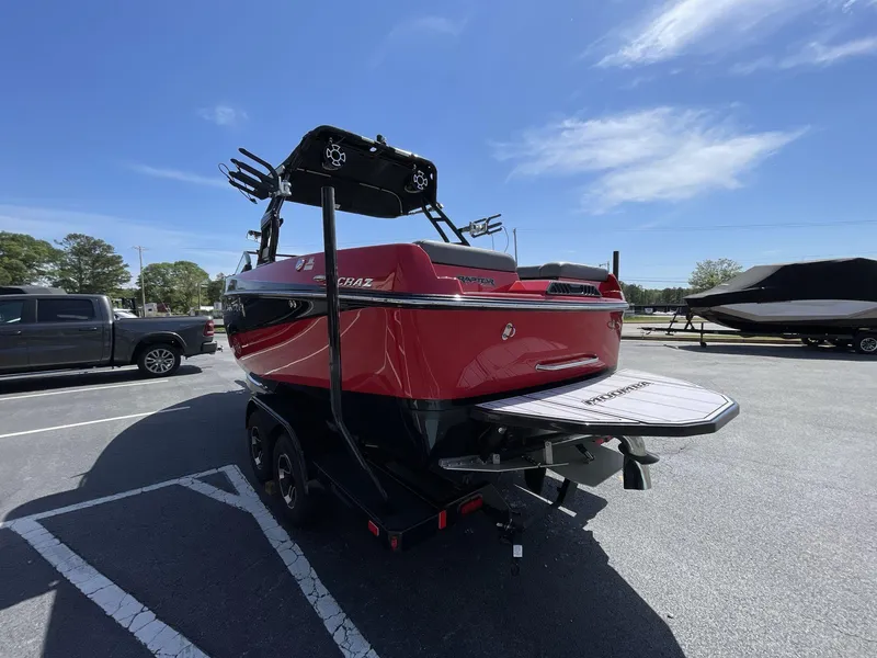 Slide: The Image of 2023 Moomba Craz boat, red and black, parked in a lot under a clear blue sky. - 10