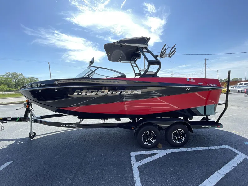 Slide: The Image of 2023 Moomba Craz boat in red and black on a trailer under a clear blue sky. - 9