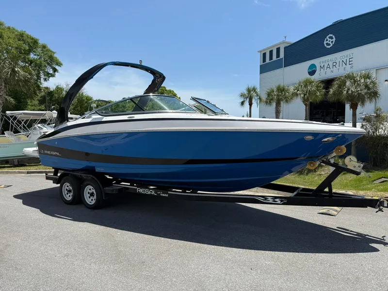 Slide: The Image of 2011 Regal 2500 Bowrider boat on trailer, parked near marine building. - 1