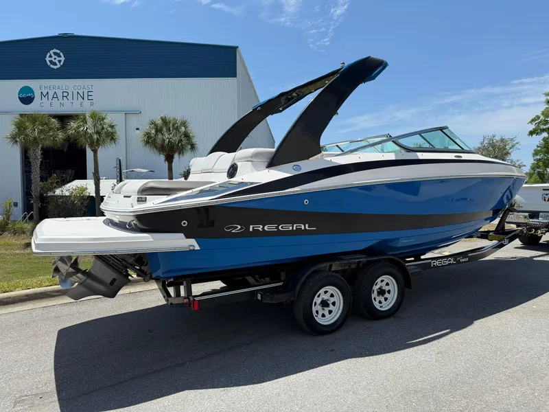 Slide: The Image of 2011 Regal 2500 Bowrider boat on trailer near marine center, blue and white design. - 4