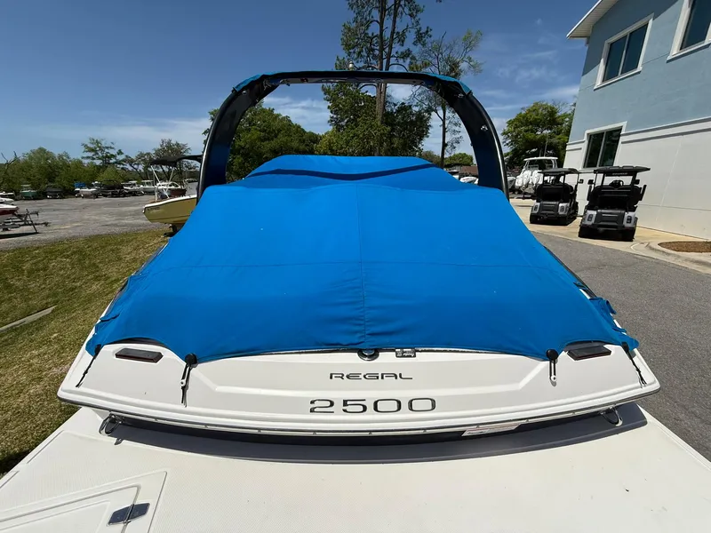 Slide: The Image of 2011 Regal 2500 Bowrider boat with blue cover, parked outdoors. - 6