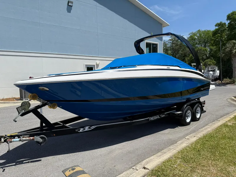Slide: The Image of 2011 Regal 2500 Bowrider boat on trailer, blue cover, parked outdoors. - 7
