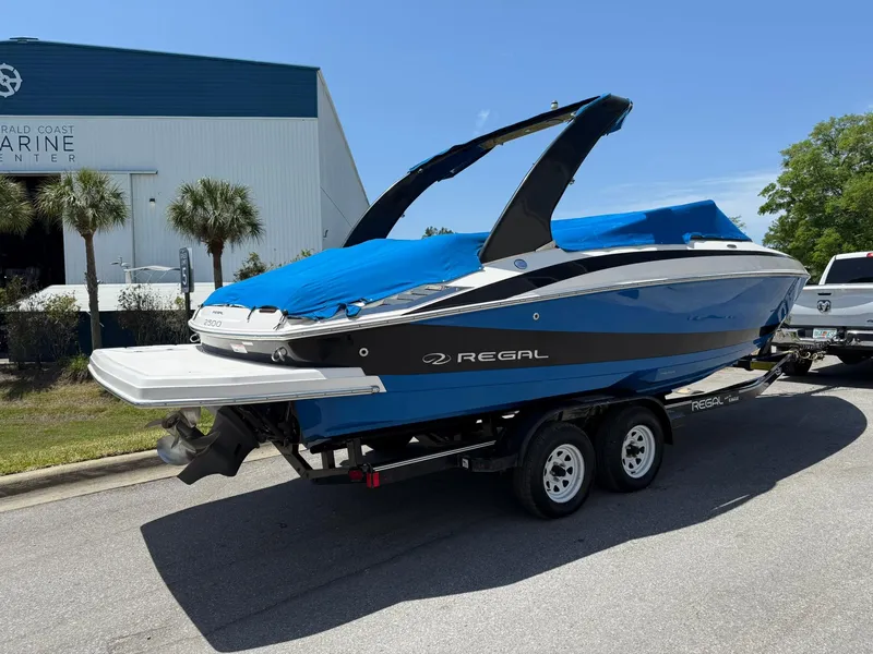 Slide: The Image of 2011 Regal 2500 Bowrider boat on trailer, blue cover, parked near marine center. - 9
